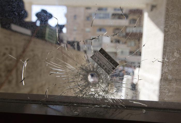 epa04494512 A bullet hole in a synagogue's front glass seen from inside and looking outwards to the Har Nof neighborhood in Jerusalem, 18 November 2014. Media reports state that two Palestinians armed with an axe, kitchen knives and a pistol killed four worshippers and injured eight others at a Jerusalem synagogue early 18 November, before being shot dead by Israeli police. The attack, which lasted seven minutes until the first police arrived, occurred during morning prayers.  EPA/JIM HOLLANDER