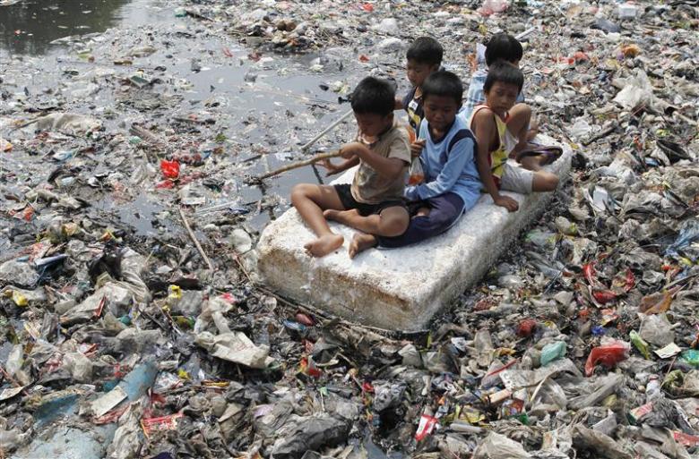 Children sitting on a makeshift raft play in a river full of rubbish in a slum area of Jakarta September 19, 2012. REUTERS/Enny Nuraheni (INDONESIA - Tags: SOCIETY TPX IMAGES OF THE DAY)