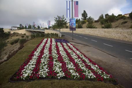 Flowers decorated as an American flag are seen on a road leading to the US Embassy compound ahead the official opening in Jerusalem, Sunday, May 13, 2018. On Monday, the United States moves its embassy in Israel from Tel Aviv to Jerusalem, the holy city at the explosive core of the Israeli-Palestinian conflict and claimed by both sides as a capital. The inauguration comes five months after President Donald Trump recognized Jerusalem as Israel's capital. (ANSA/AP Photo/Ariel Schalit) [CopyrightNotice: Copyright 2018 The Associated Press. All rights reserved.]