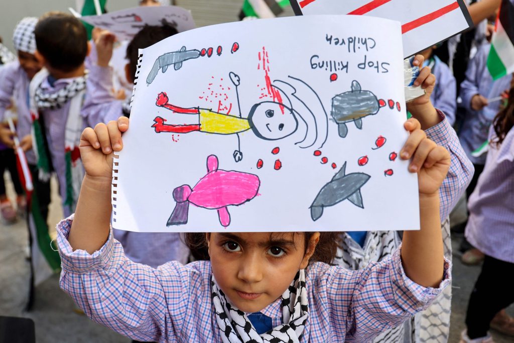 A Palestinian child holds up a drawing as refugee children living in Lebanese camps take part in a sit-in protest in front of the International Red Cross in the capital Beirut denouncing the killing of children in Gaza, on November 7, 2023, amid the ongoing battles between Israel and the militant group Hamas. (Photo by ANWAR AMRO / AFP)