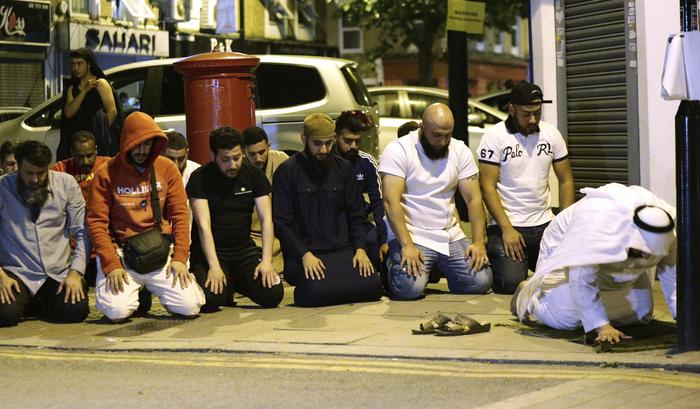 Local people observe prayers at Finsbury Park where a vehicle struck pedestrians in London Monday, June 19, 2017. Police say a vehicle struck pedestrians near a mosque in north London, leaving several casualties and one person was arrested. (Yui Mok/PA via AP) [CopyrightNotice: PA]