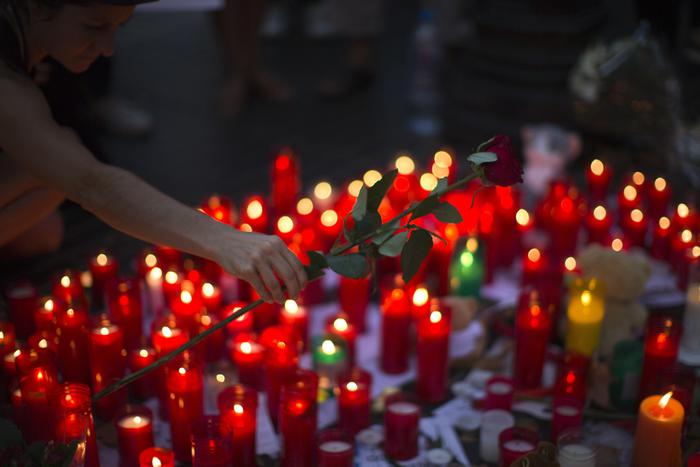 A woman places flowers on a memorial after a van attack that killed at least 13, in central Barcelona, Spain, Friday, Aug. 18, 2017. Police on Friday shot and killed five people carrying bomb belts who were connected to the Barcelona van attack, as the manhunt intensified for the perpetrators of Europe's latest rampage claimed by the Islamic State group. (ANSA/AP Photo/Emilio Morenatti) [CopyrightNotice: Copyright 2017 The Associated Press. All rights reserved.]