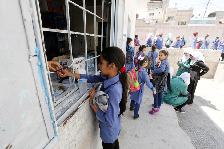 A refugee schoolchild buys sweets on her first day of the new school year at one of the UNRWA schools at a Palestinian refugee camp al Wehdat, in Amman, Jordan, September 1, 2016.  REUTERS/Muhammad Hamed