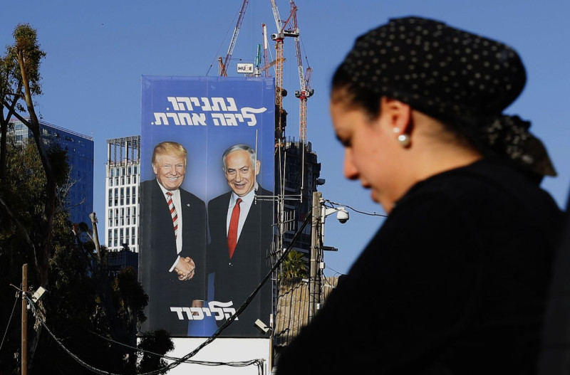A walks past a giant election billboard showing Israeli Prime Minister Benjamin Netanyahu and US President Donald Trump shaking hands, in the Israeli coastal city of Tel Aviv, on February 3, 2019. The writing on the billboard reads in Hebrew "Netanyahu, in another league". (Photo by JACK GUEZ / AFP)        (Photo credit should read JACK GUEZ/AFP/Getty Images)