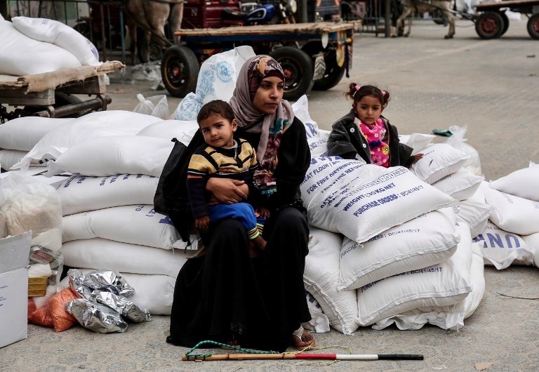 A Palestinian woman sits with a child after receiving food supplies from the United Nations' offices at the United Nations' offices in the Khan Yunis refugee camp in the southern Gaza Strip on February 11, 2018.
On January 16, Washington held back $65 million that had been earmarked for the UN Relief and Works Agency for Palestinian refugees (UNRWA), but the State Department denied the freeze was to punish the Palestinian leadership, which has cut ties with President Donald Trump's administration following his recognition of Jerusalem as Israel's capital last year, with a spokeswoman saying it was linked to necessary "reform" of UNRWA. / AFP PHOTO / SAID KHATIB